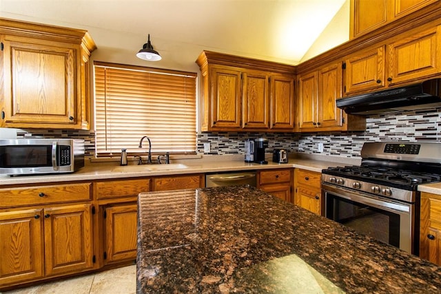 717 Hunters Run, Midwest City, OK 73130 - kitchen with appliances with stainless steel finishes, under cabinet range hood, a sink, tasteful backsplash, and brown cabinets