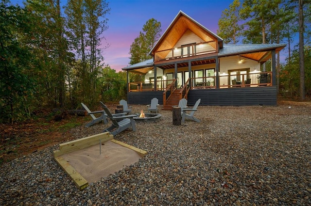 48 Cedar Hills Trl, Broken Bow, OK 74728 - back of house at dusk with an outdoor fire pit, ceiling fan, metal roof, a wooden deck, and a patio