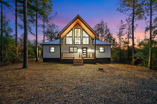 48 Cedar Hills Trl, Broken Bow, OK 74728 - back of house at dusk featuring metal roof and covered porch