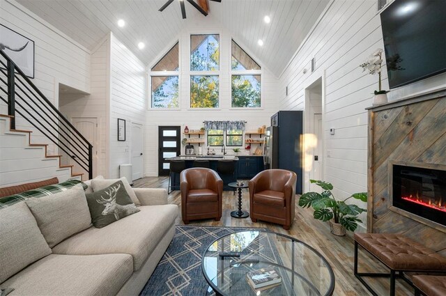 48 Cedar Hills Trl, Broken Bow, OK 74728 - living area featuring high vaulted ceiling, light wood-style floors, wood walls, stairway, and ceiling fan