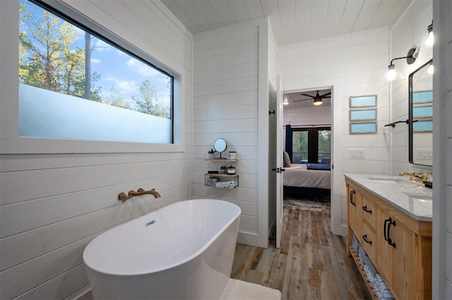 48 Cedar Hills Trl, Broken Bow, OK 74728 - ensuite bathroom featuring wood finished floors, a freestanding bath, wooden walls, vanity, and a ceiling fan