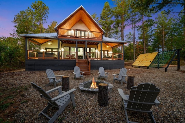 48 Cedar Hills Trl, Broken Bow, OK 74728 - back of property at dusk featuring an outdoor fire pit, metal roof, a deck, and stairway