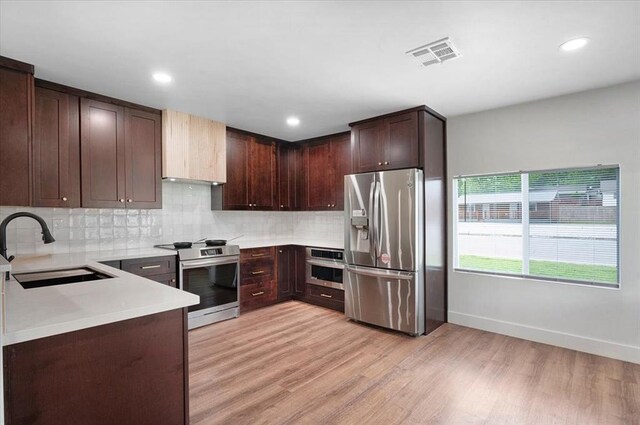 825 W Colorado Ave, Chickasha, OK 73018 - kitchen with appliances with stainless steel finishes, a sink, light wood-style flooring, light countertops, and backsplash