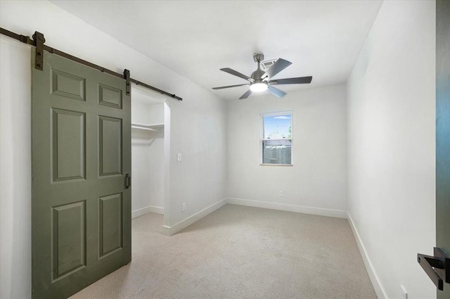 825 W Colorado Ave, Chickasha, OK 73018 - unfurnished bedroom featuring a barn door, light carpet, baseboards, and a walk in closet