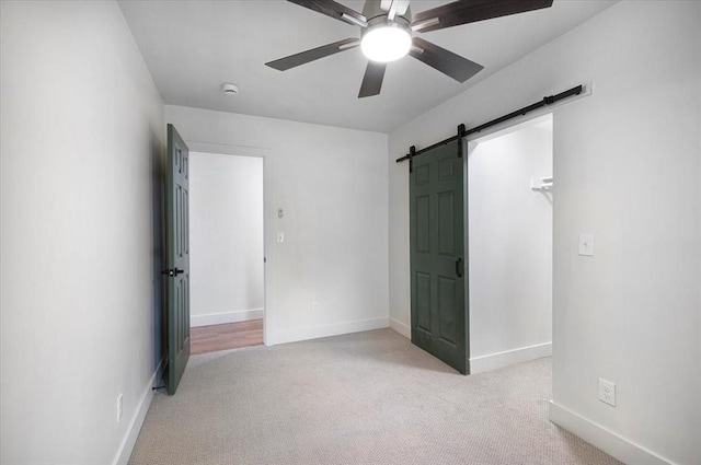 825 W Colorado Ave, Chickasha, OK 73018 - unfurnished bedroom with a barn door, carpet, baseboards, and a ceiling fan