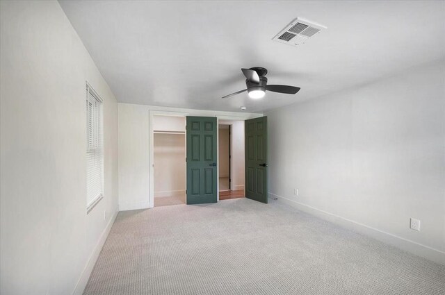 825 W Colorado Ave, Chickasha, OK 73018 - unfurnished bedroom featuring baseboards, light carpet, a closet, ceiling fan, and a walk in closet