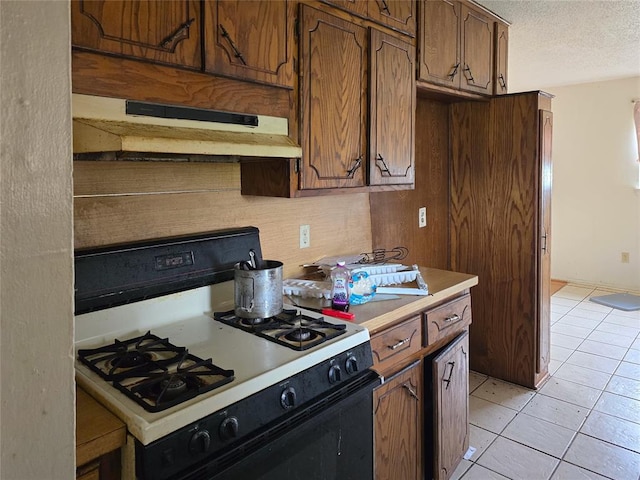 3401 SW Abilene Dr, Lawton, OK 73501 - kitchen featuring gas range oven, under cabinet range hood, light tile patterned floors, light countertops, and a textured ceiling