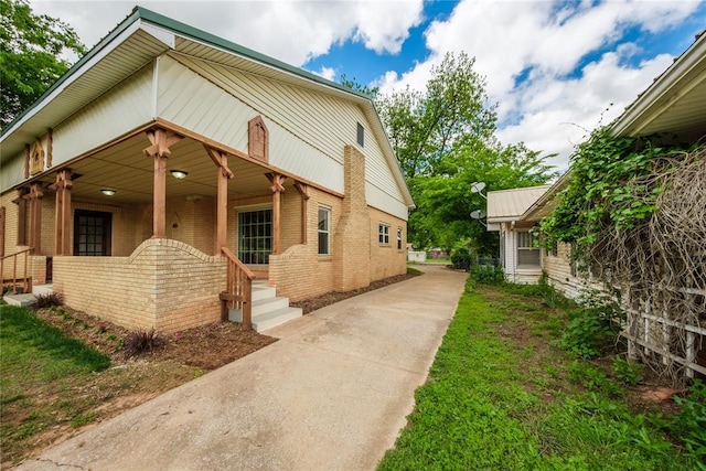 view of front of property with brick siding, a porch, and concrete driveway