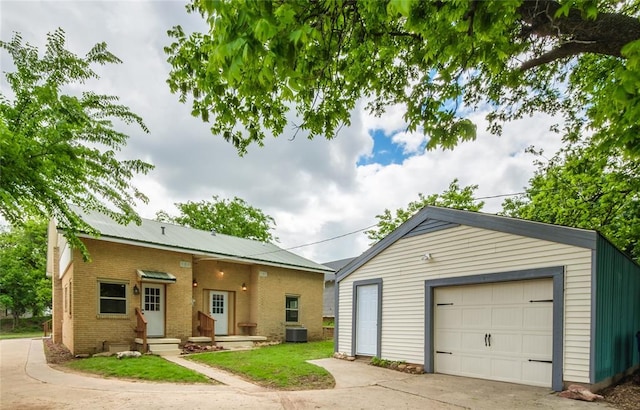 view of front of property with an outbuilding, brick siding, a detached garage, concrete driveway, and central AC unit