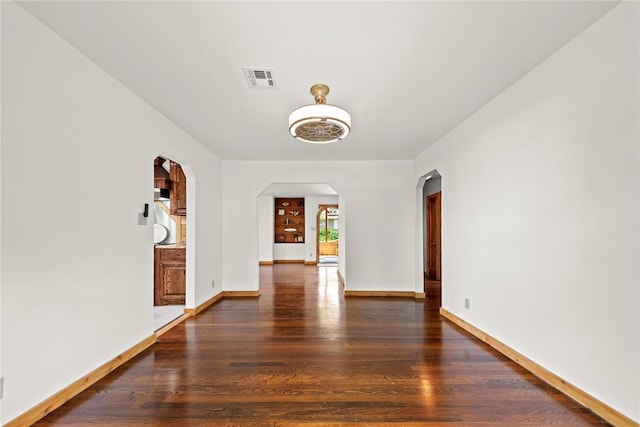 unfurnished dining area featuring arched walkways, wood finished floors, and baseboards