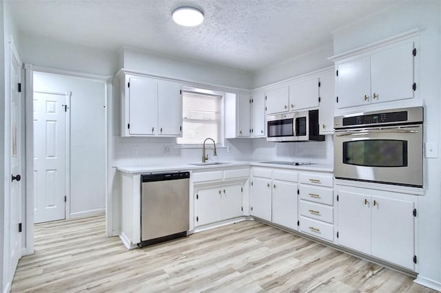 2528 Oakridge Dr, Bethany, OK 73008 - kitchen with appliances with stainless steel finishes, a sink, light wood-style floors, light countertops, and a textured ceiling
