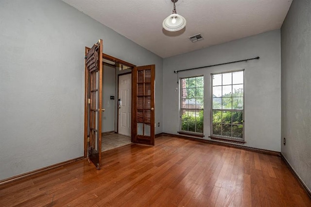 2105 SW 124th St, Oklahoma City, OK 73170 - unfurnished room with wood finished floors, baseboards, french doors, and a textured wall