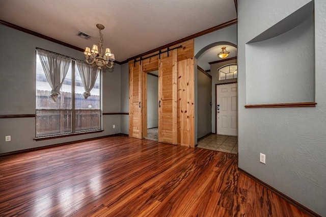 2105 SW 124th St, Oklahoma City, OK 73170 - unfurnished dining area featuring ornamental molding, arched walkways, wood finished floors, a chandelier, and baseboards