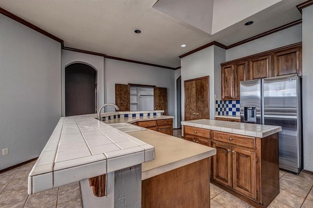 2105 SW 124th St, Oklahoma City, OK 73170 - kitchen with a large island, stainless steel refrigerator with ice dispenser, a sink, crown molding, and arched walkways