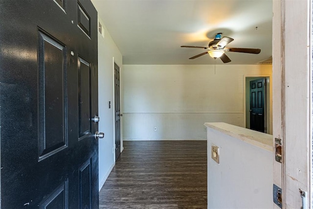 foyer featuring ceiling fan, dark wood-style flooring, and a wainscoted wall