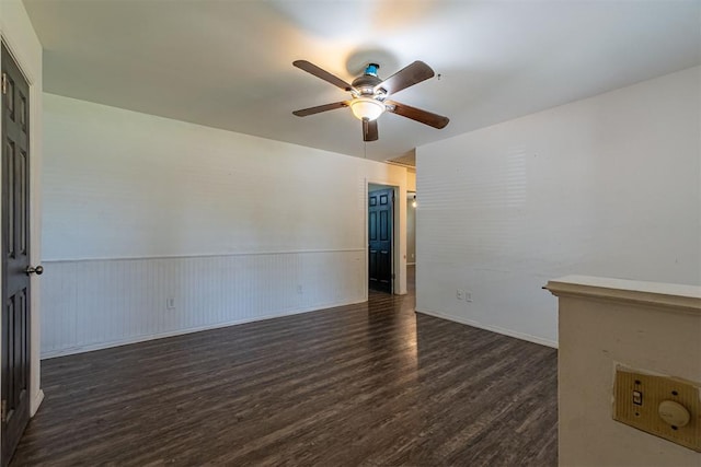 unfurnished room with ceiling fan, dark wood finished floors, and a wainscoted wall