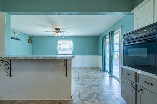 kitchen with oven, healthy amount of natural light, a ceiling fan, light countertops, and wainscoting