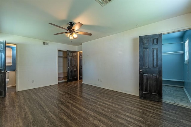 unfurnished bedroom featuring wood finished floors, baseboards, a ceiling fan, and ensuite bath
