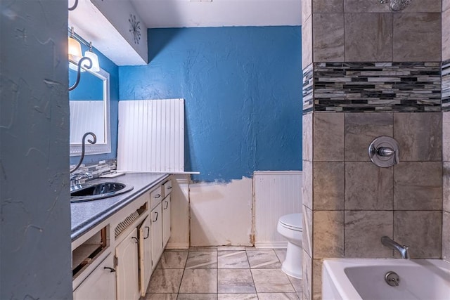 bathroom with a textured wall, toilet, vanity, a wainscoted wall, and tub / shower combination