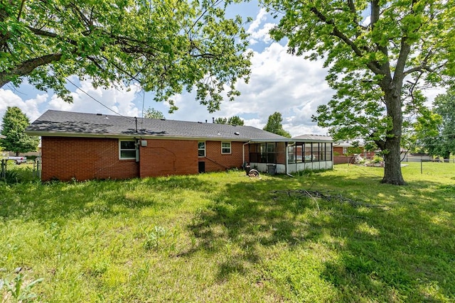 rear view of property featuring a sunroom and brick siding