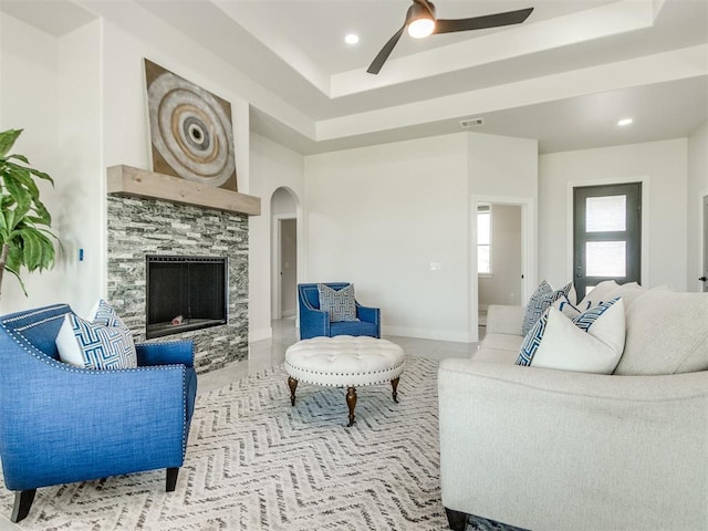 4850 Ranchero Dr, Edmond, OK 73025 - tiled living area with a tray ceiling, a ceiling fan, a tiled fireplace, arched walkways, and recessed lighting