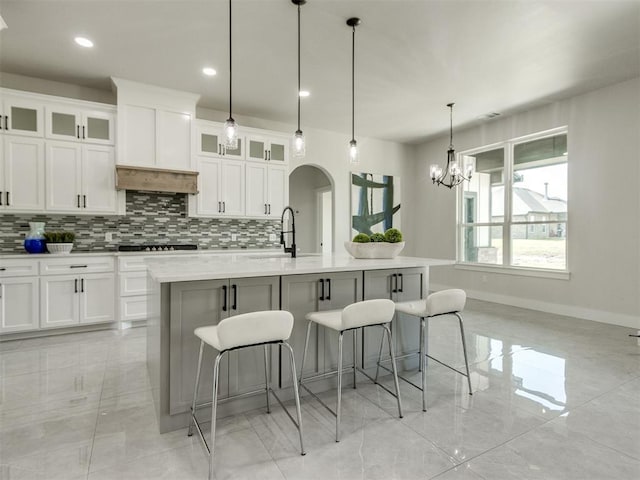 4850 Ranchero Dr, Edmond, OK 73025 - kitchen with a sink, tasteful backsplash, a kitchen bar, black electric cooktop, and white cabinetry