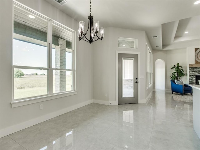 4850 Ranchero Dr, Edmond, OK 73025 - foyer with a chandelier, baseboards, arched walkways, and a fireplace