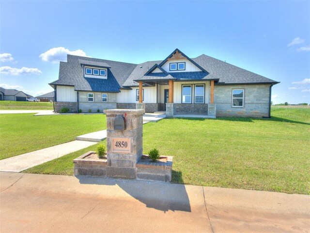 4850 Ranchero Dr, Edmond, OK 73025 - craftsman house with stone siding, a front yard, a shingled roof, and board and batten siding