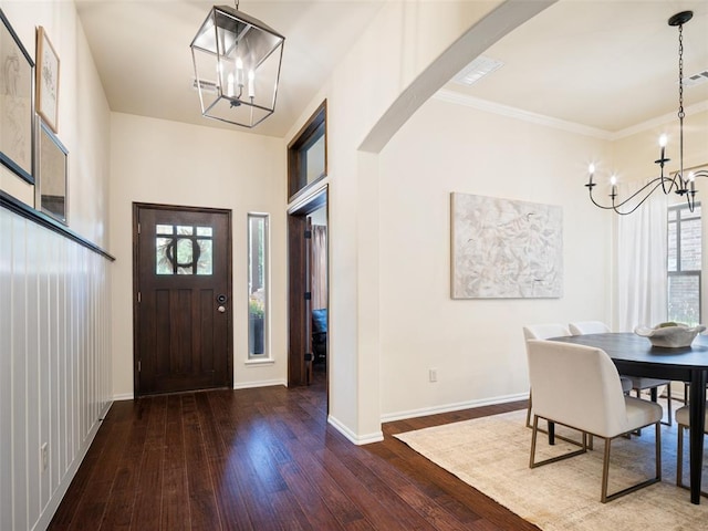 foyer entrance featuring a chandelier, hardwood / wood-style flooring, baseboards, arched walkways, and ornamental molding