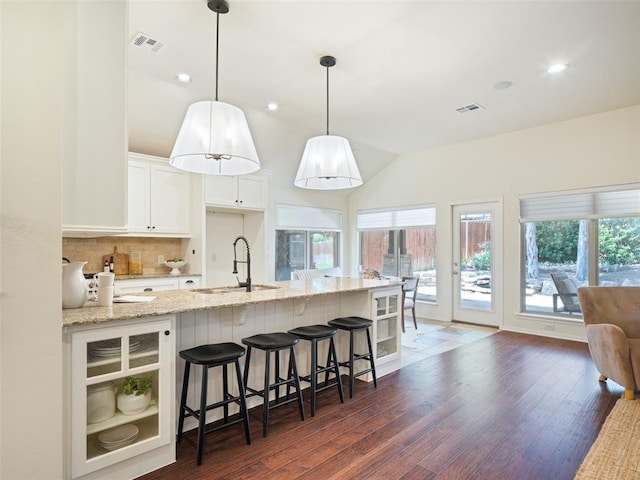 kitchen featuring a sink, light stone counters, tasteful backsplash, dark wood-type flooring, and white cabinets