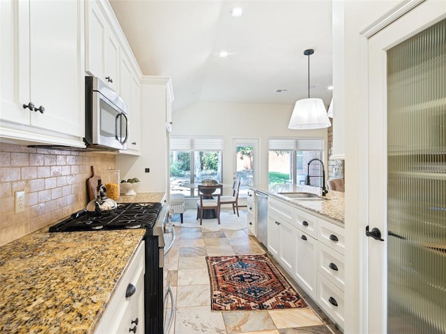 kitchen with appliances with stainless steel finishes, a sink, lofted ceiling, backsplash, and white cabinetry