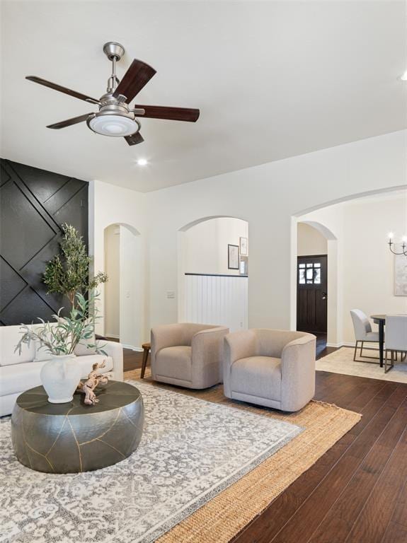 living room with arched walkways, dark wood-style flooring, a ceiling fan, recessed lighting, and a chandelier