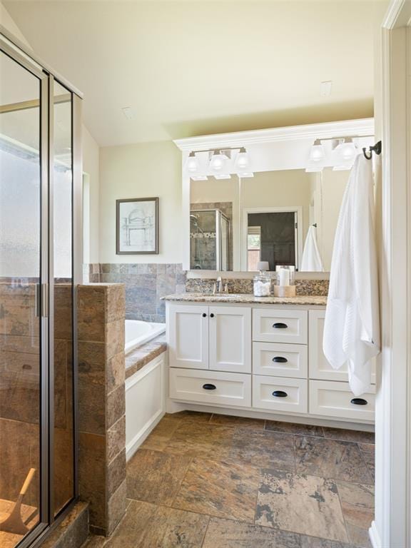 full bathroom with vanity, a bath, a stall shower, and stone tile flooring