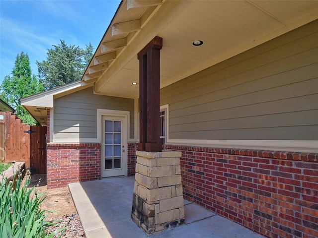property entrance featuring a patio, fence, and brick siding