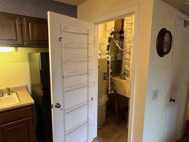 hallway with water heater, a sink, and concrete floors