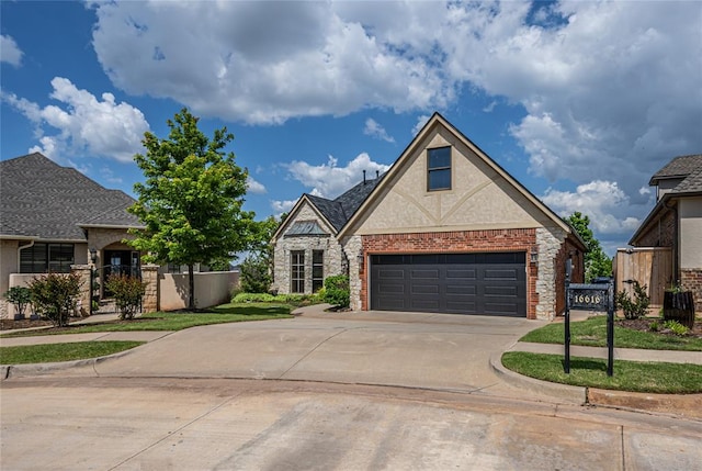 view of front of property featuring driveway, stone siding, fence, and a garage