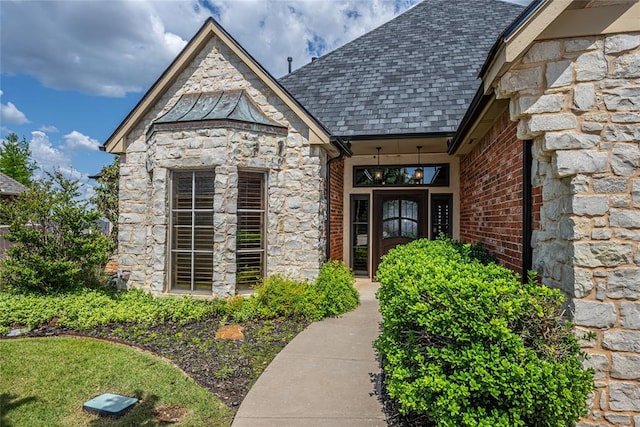 view of exterior entry with stone siding and brick siding