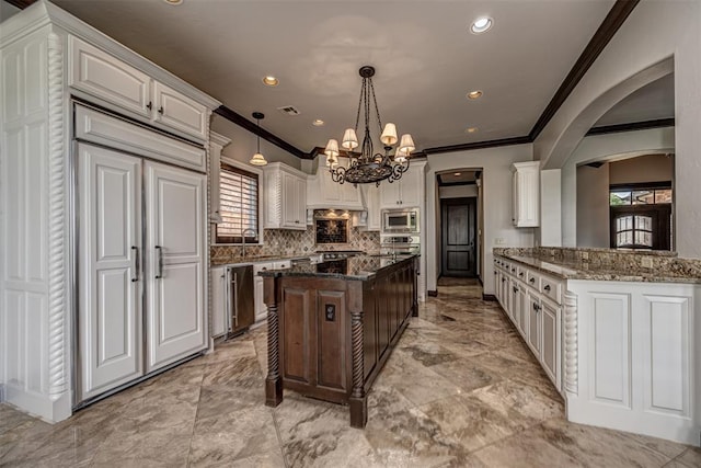 kitchen featuring built in appliances, crown molding, arched walkways, a kitchen island, and white cabinets