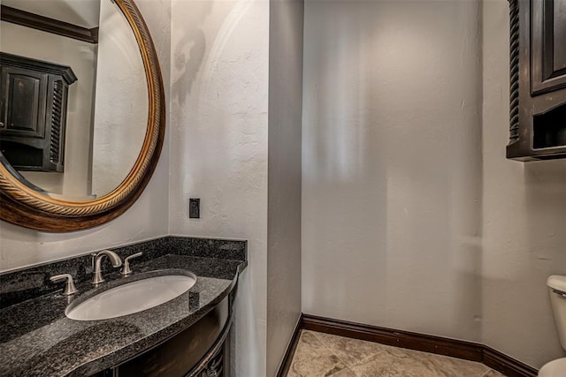 half bath with baseboards, toilet, and vanity