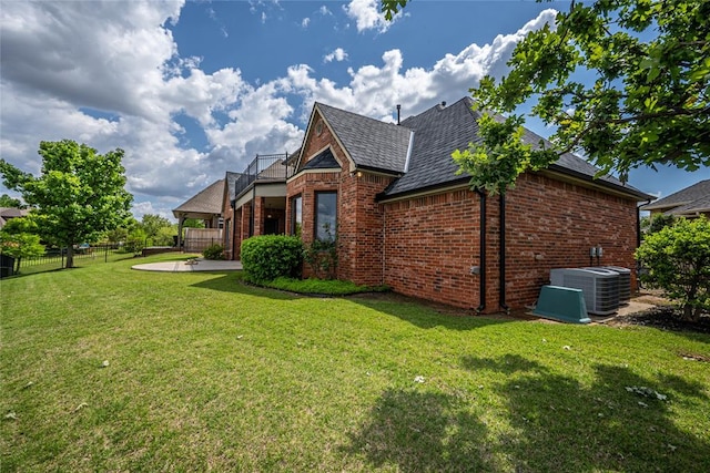 view of home's exterior featuring brick siding, central AC, a balcony, and a patio area