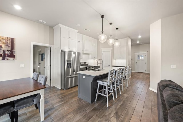9117 NW 123rd St, Yukon, OK 73099 - kitchen with stainless steel appliances, a sink, white cabinets, a kitchen island with sink, and dark wood finished floors