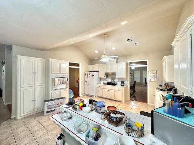 kitchen featuring white appliances, light tile patterned floors, vaulted ceiling, a ceiling fan, and white cabinets