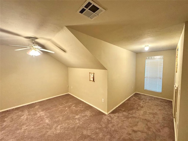 additional living space with carpet floors, vaulted ceiling, baseboards, ceiling fan, and a textured ceiling