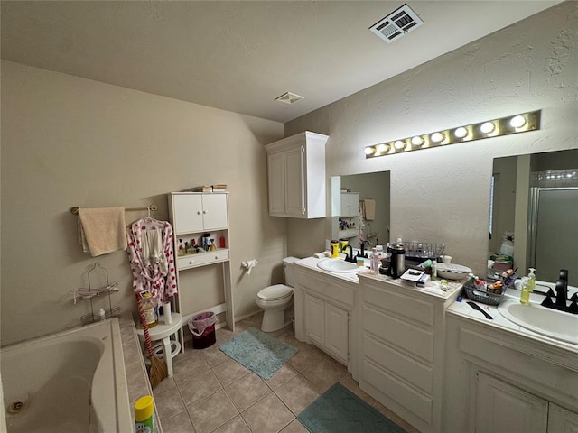bathroom featuring tile patterned flooring, a bath, double vanity, and toilet