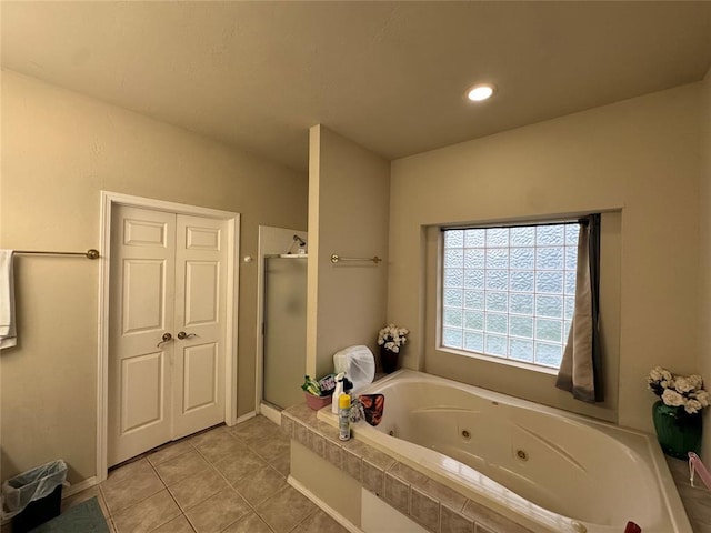 bathroom featuring a shower stall, tile patterned flooring, a tub with jets, and baseboards