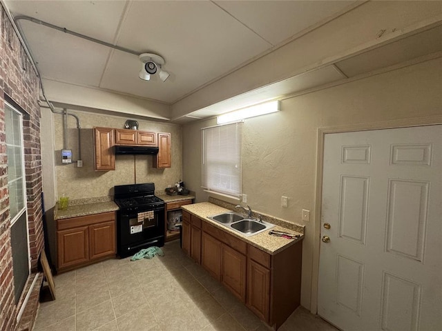 kitchen featuring a sink, gas stove, under cabinet range hood, brown cabinets, and light countertops