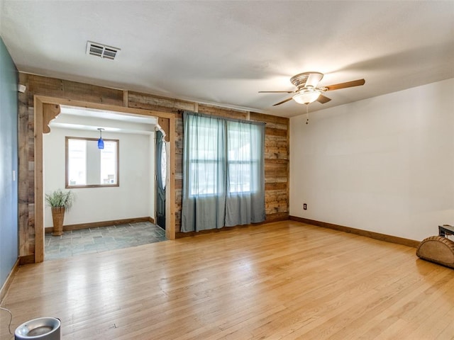 3208 NW 34th St, Oklahoma City, OK 73112 - empty room featuring light wood-type flooring, ceiling fan, baseboards, and wooden walls