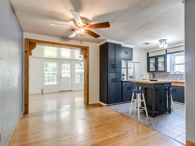 3208 NW 34th St, Oklahoma City, OK 73112 - kitchen with blue cabinets, tasteful backsplash, ceiling fan, light wood-style flooring, and baseboards