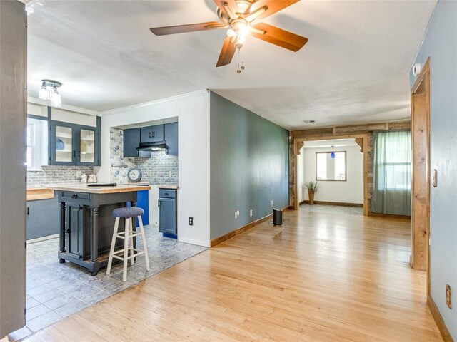 3208 NW 34th St, Oklahoma City, OK 73112 - kitchen featuring light wood-style flooring, extractor fan, backsplash, blue cabinets, and butcher block counters