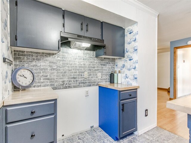 3208 NW 34th St, Oklahoma City, OK 73112 - kitchen featuring under cabinet range hood, decorative backsplash, light countertops, baseboards, and crown molding